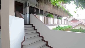 A staircase with a red border leading to a covered outdoor area with greenery. - Hotel Lestari Near Lippo Plaza Mall Jember (Patrang)