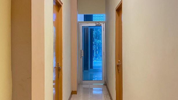 A hallway with wooden doors on either side, leading to a glass door at the end. - RedDoorz @ Jalan Morotai Lampung (Bandar Lampung)