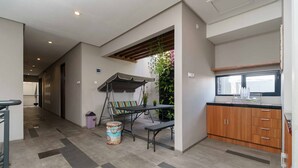 A modern kitchen with wooden cabinets, a dining area with a bench, and a small table. - RedDoorz Plus near Radio Dalam 3 (Jakarta)