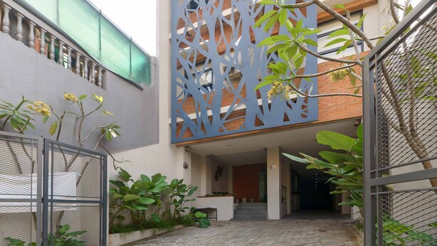 A modern building with a geometric facade, a covered entrance, and a staircase leading to the interior. - RedDoorz Plus near Radio Dalam 3 (Jakarta)