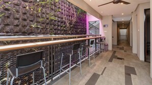 A modern bar area with a high, textured wall and a ceiling fan. - RedDoorz Plus near Radio Dalam 3 (Jakarta)