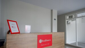 A reception desk with a RedDoorz sign, a framed partnership certificate, and a small informational poster. - RedDoorz near Sleman City Hall 2 (Ngaglik)