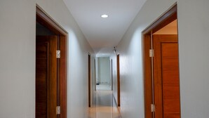 A corridor with wooden doors on either side, leading to a room with a ceiling fan and recessed lighting. - RedDoorz near Sleman City Hall 2 (Ngaglik)