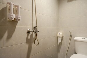 Un baño con ducha, inodoro y dispensador de toallas.