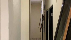 En smal hall med ett randigt golv, en vit vägg och en dörr längst ner.