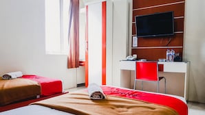 Habitación de hotel con dos camas, un escritorio, una silla, un televisor y una ventana con cortinas.