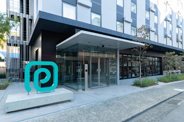 A modern building with a glass entrance and a teal logo. - Prince Smart Inn Atami (Atami)