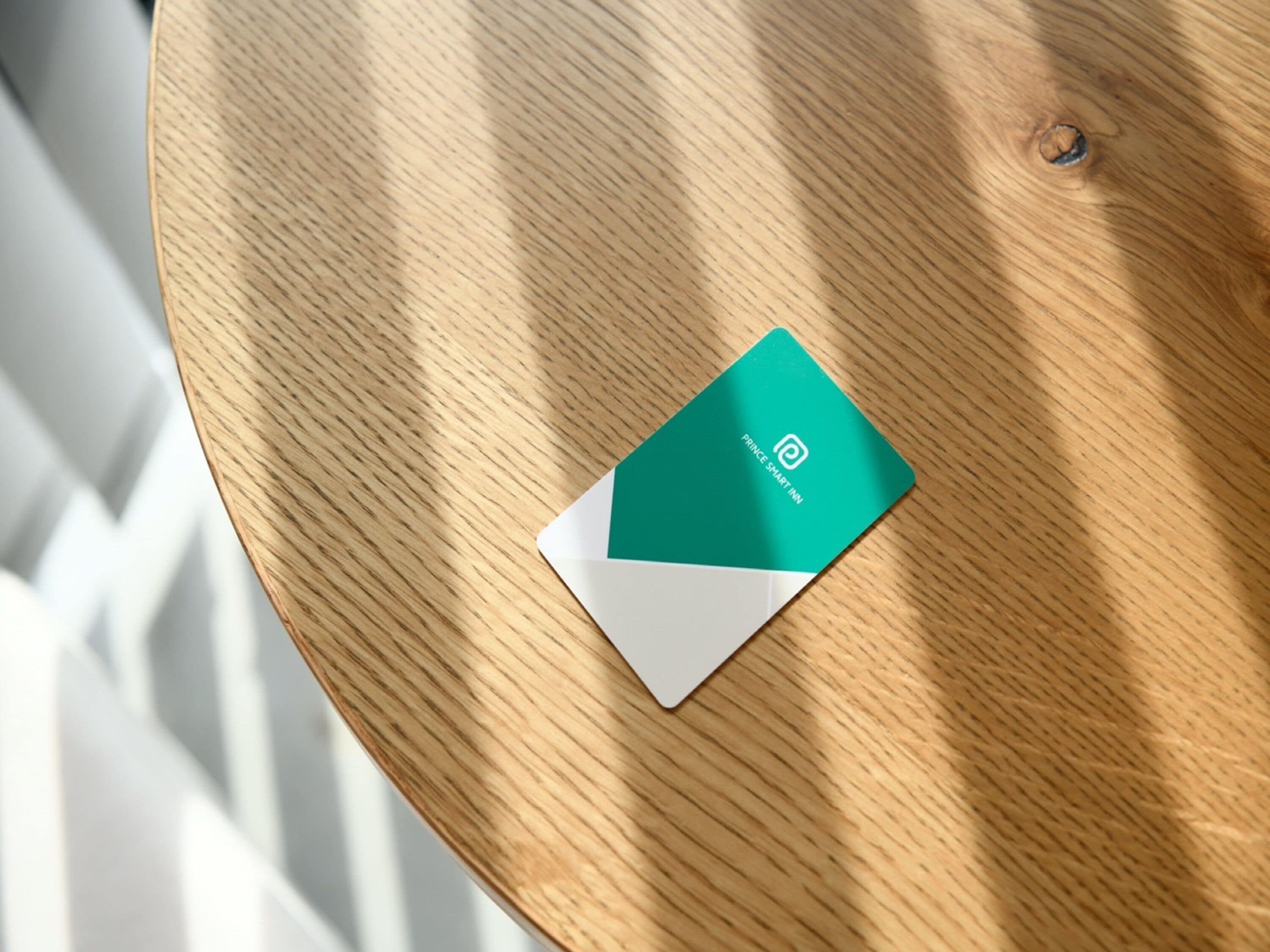 A green and white business card on a wooden table.