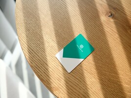A green and white business card on a wooden table.