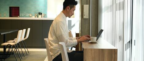 A person working at a wooden desk in a modern office space with a view of a cityscape through large windows.