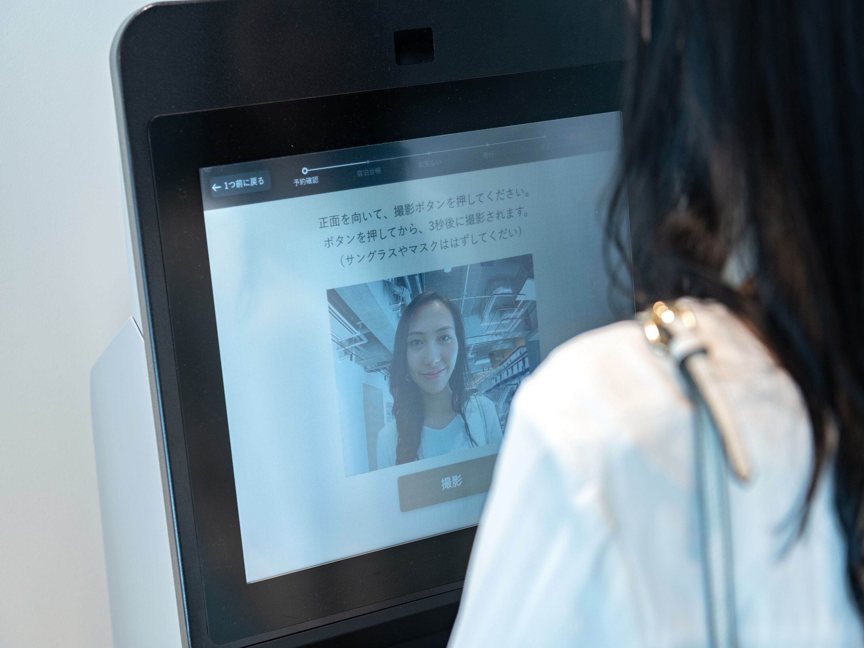 Una pantalla digital con texto en japonés y una fotografía de una persona.