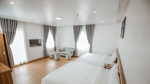 Une chambre d’hôtel moderne équipée de deux lits, d’un canapé, d’une télévision et d’un bureau en bois.