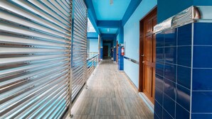A corridor with blue walls and wooden flooring, leading to a door with a metal handle. - RedDoorz Premium @ Casa Ghilda Resort Olongapo City (Olongapo)