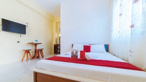 A hotel room with a bed, a TV mounted on the wall, a small table, and a chair. - RedDoorz Premium @ Casa Ghilda Resort Olongapo City (Olongapo)