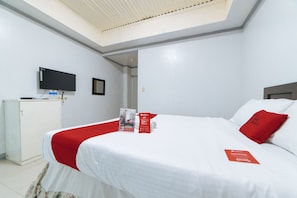 A hotel room with a bed, a desk, a flat-screen TV, and a red pillow. - RedDoorz Plus @ Subic 2n2 Beach Resort Zambales (Subic)
