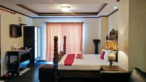 Una habitación de hotel con una cama, televisor, escritorio y lámpara.