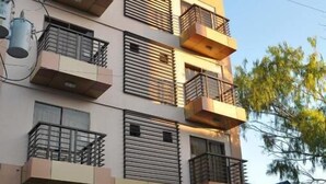 Un edificio de varios pisos con balcones, una entrada cubierta y un letrero que dice 'New Egg Family Resort'.