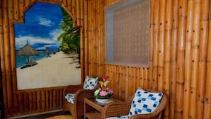 A room with a beach-themed mural, wicker furniture, and a bamboo wall. - RedDoorz Plus @ Sla Divina Panglao Bohol (Panglao)