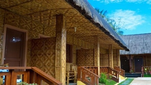 A traditional wooden building with a thatched roof, wooden columns, and a wooden porch with railings. - RedDoorz Plus @ Sla Divina Panglao Bohol (Panglao)