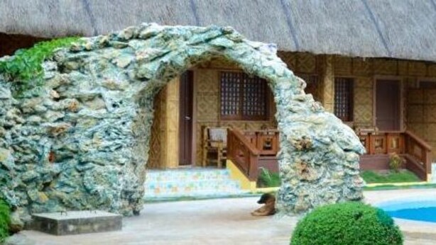 A traditional thatched-roof building with a stone archway leading to a pool area. - RedDoorz Plus @ Sla Divina Panglao Bohol (Panglao)