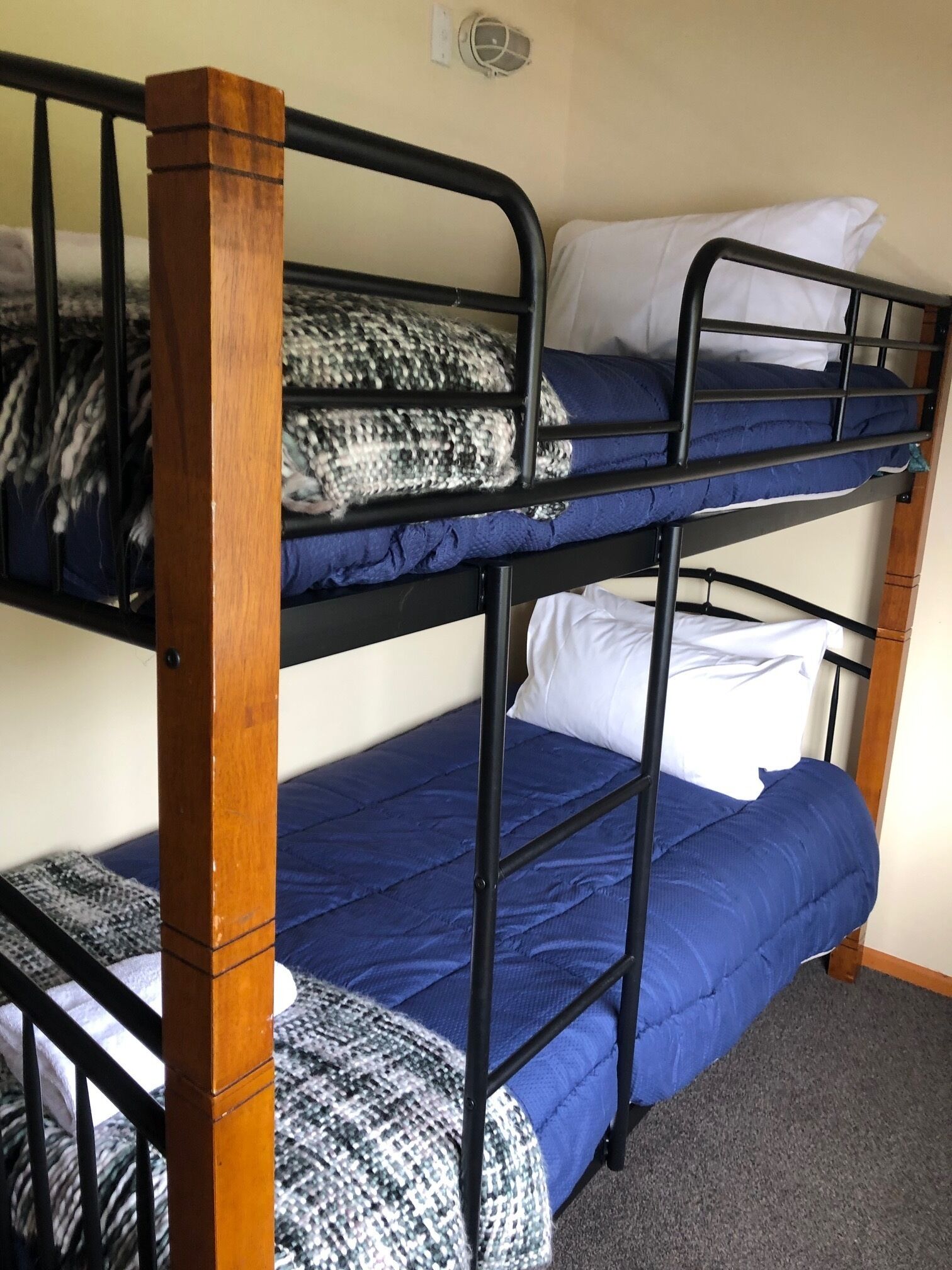 A bunk bed with wooden posts and blue bedding.