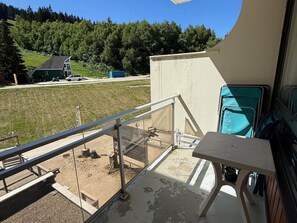 A balcony with a view of a grassy area and a building in the distance.