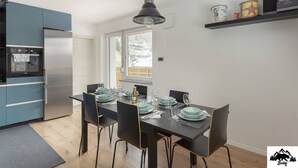 A modern kitchen with a dining area, featuring a large window, a built-in oven, and a shelf with canned goods. - Apartment Brlog (Zgornje Gorje)