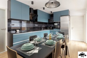 Una cocina moderna con armarios azules, una encimera negra y una zona de comedor preparada para seis personas.