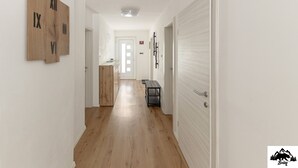 A hallway with wooden flooring, a wooden clock, and a bench. - Apartment Brlog (Zgornje Gorje)