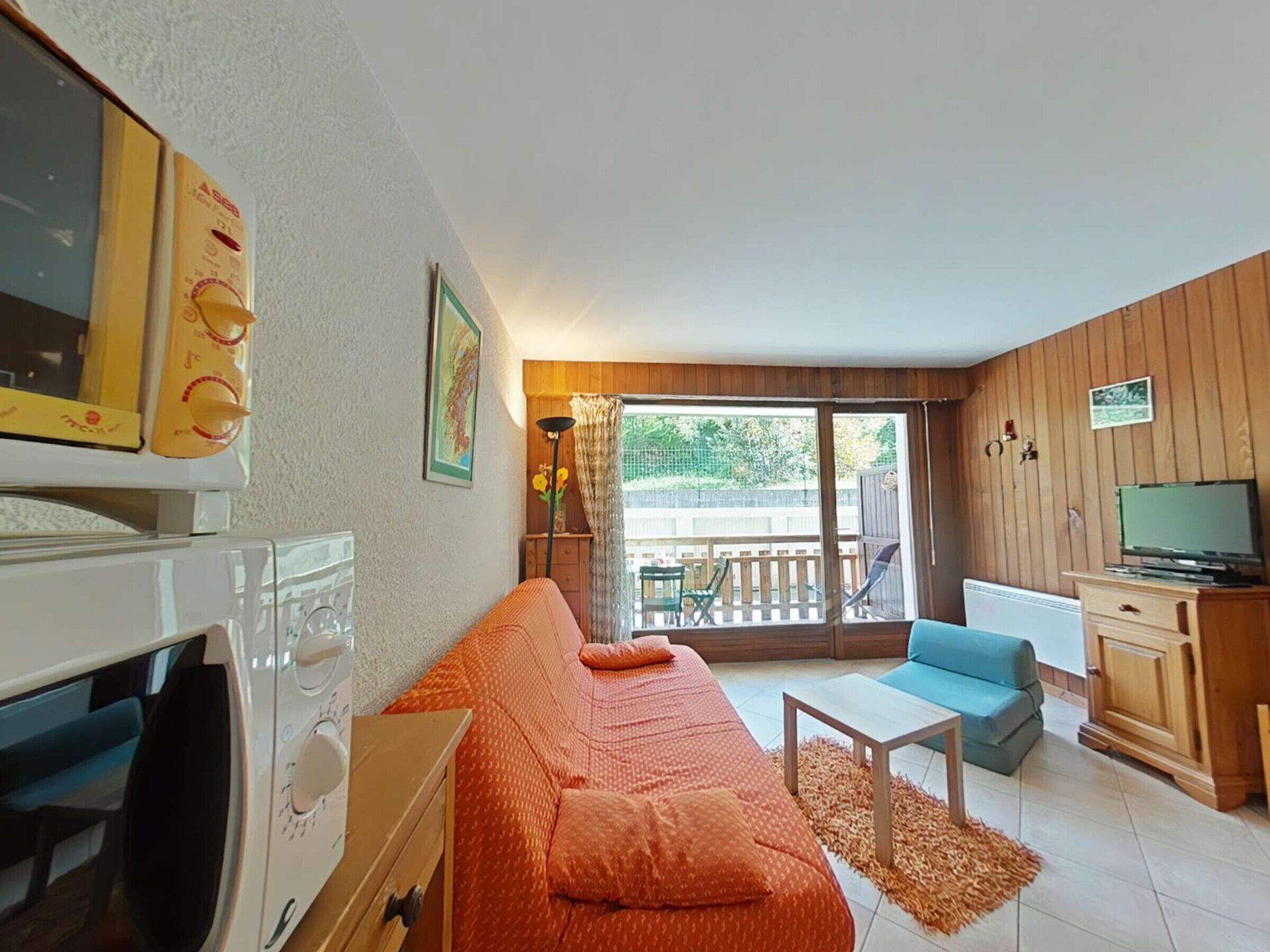 Un salón acogedor con sofá, una mesita, televisión y balcón con vistas.