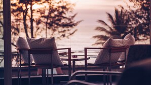Two chairs with patterned cushions, a small table, and a view of the ocean and trees. - Villa Beachside Kata Noi (Karon)