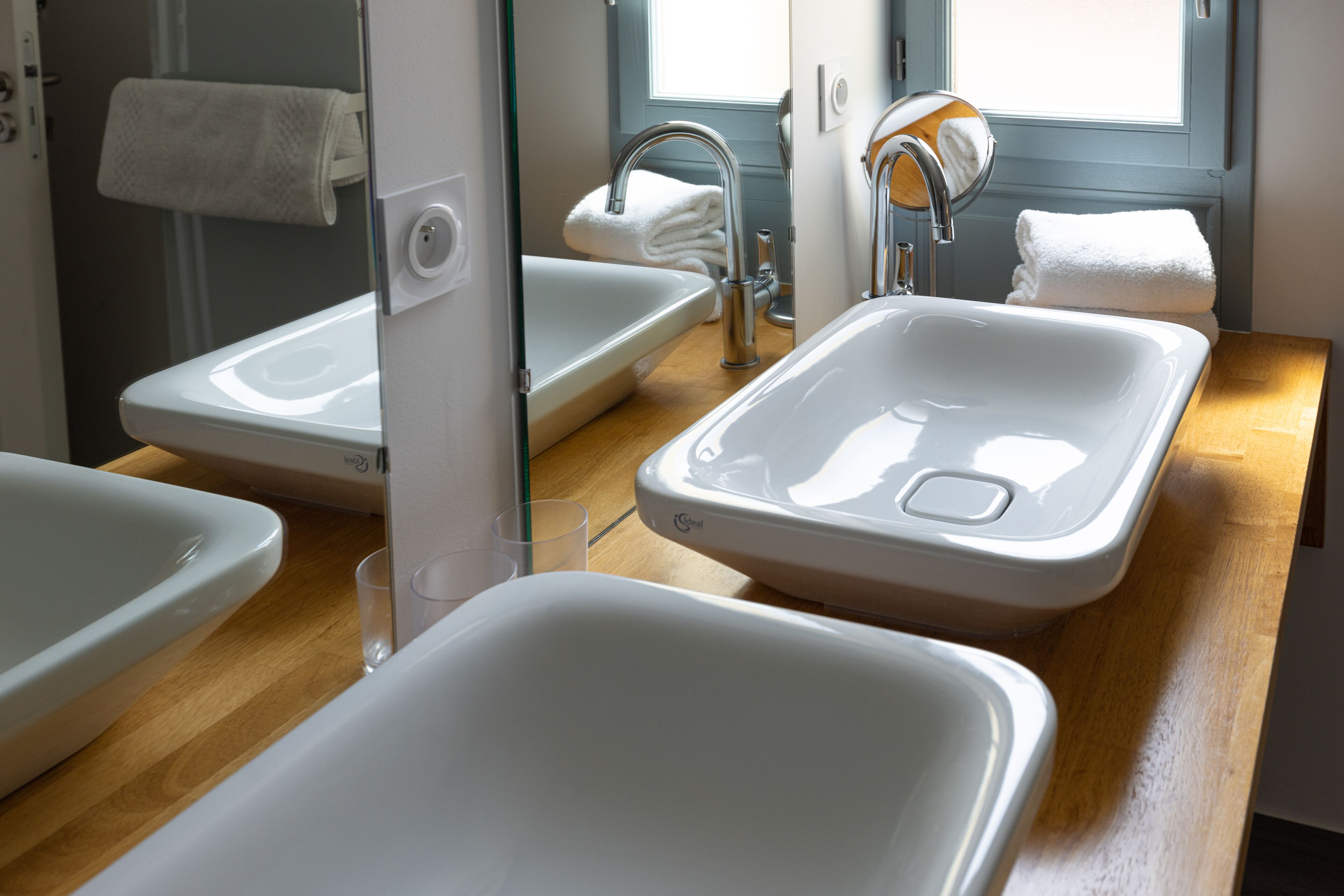Une salle de bain avec deux lavabos, un miroir et une fenêtre.
