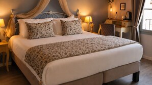 A bedroom with a bed, bedside tables, a desk, a hanging light fixture, and a window with curtains. - Hôtel des Augustins - Boutique Hôtel - Restaurant Gastronomique (Saint-Cyprien)