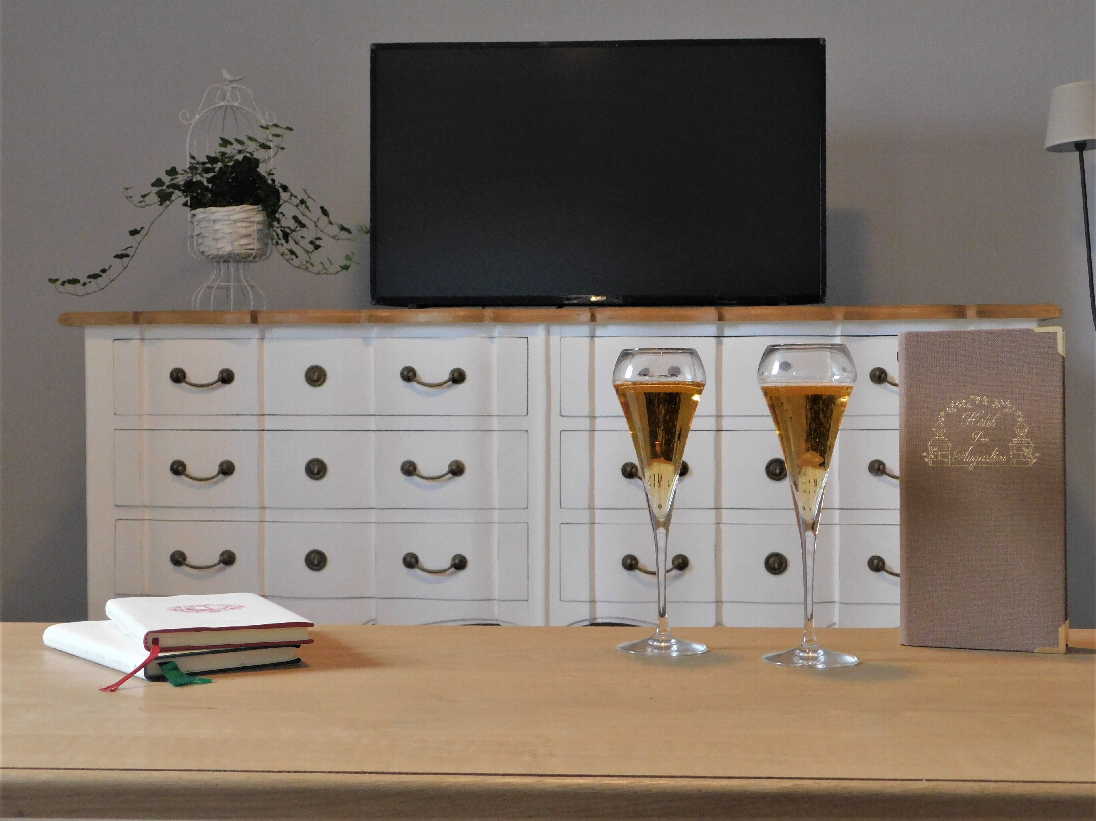 Une table en bois sur laquelle sont posés deux flûtes à champagne, un livre et une boîte décorative.