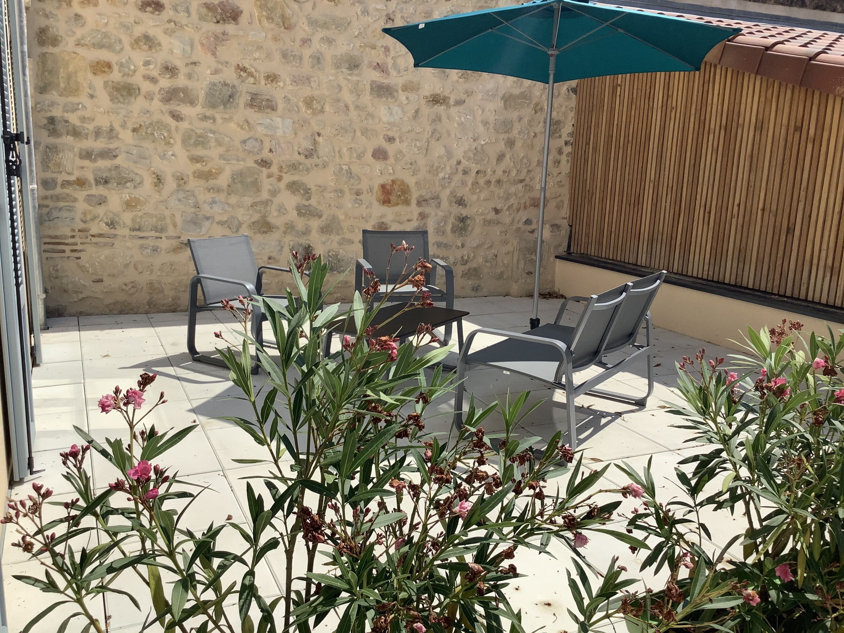 An outdoor seating area with stone walls, a wooden fence, and potted plants.