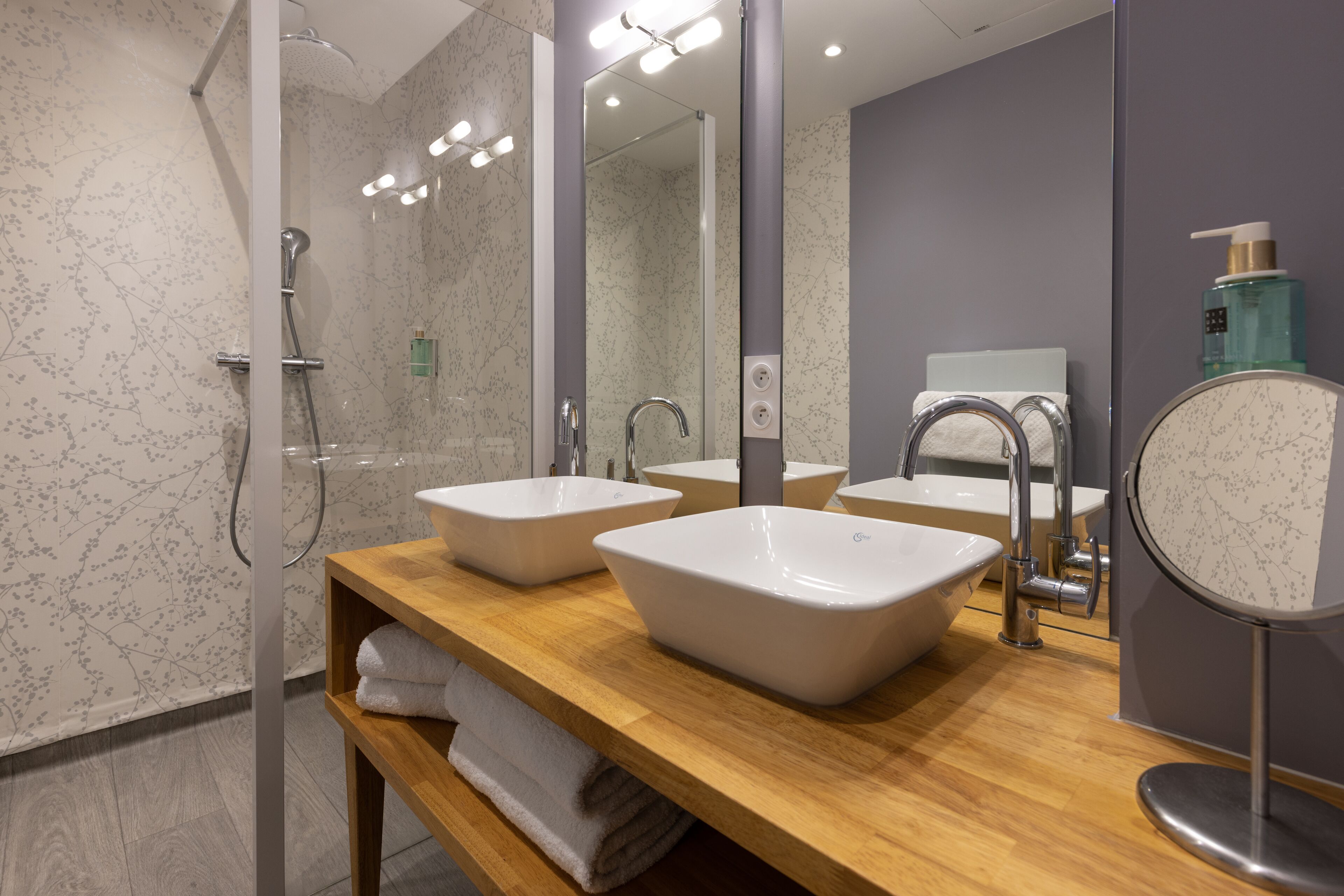 Un baño moderno con dos lavabos, ducha y tocador con espejo.