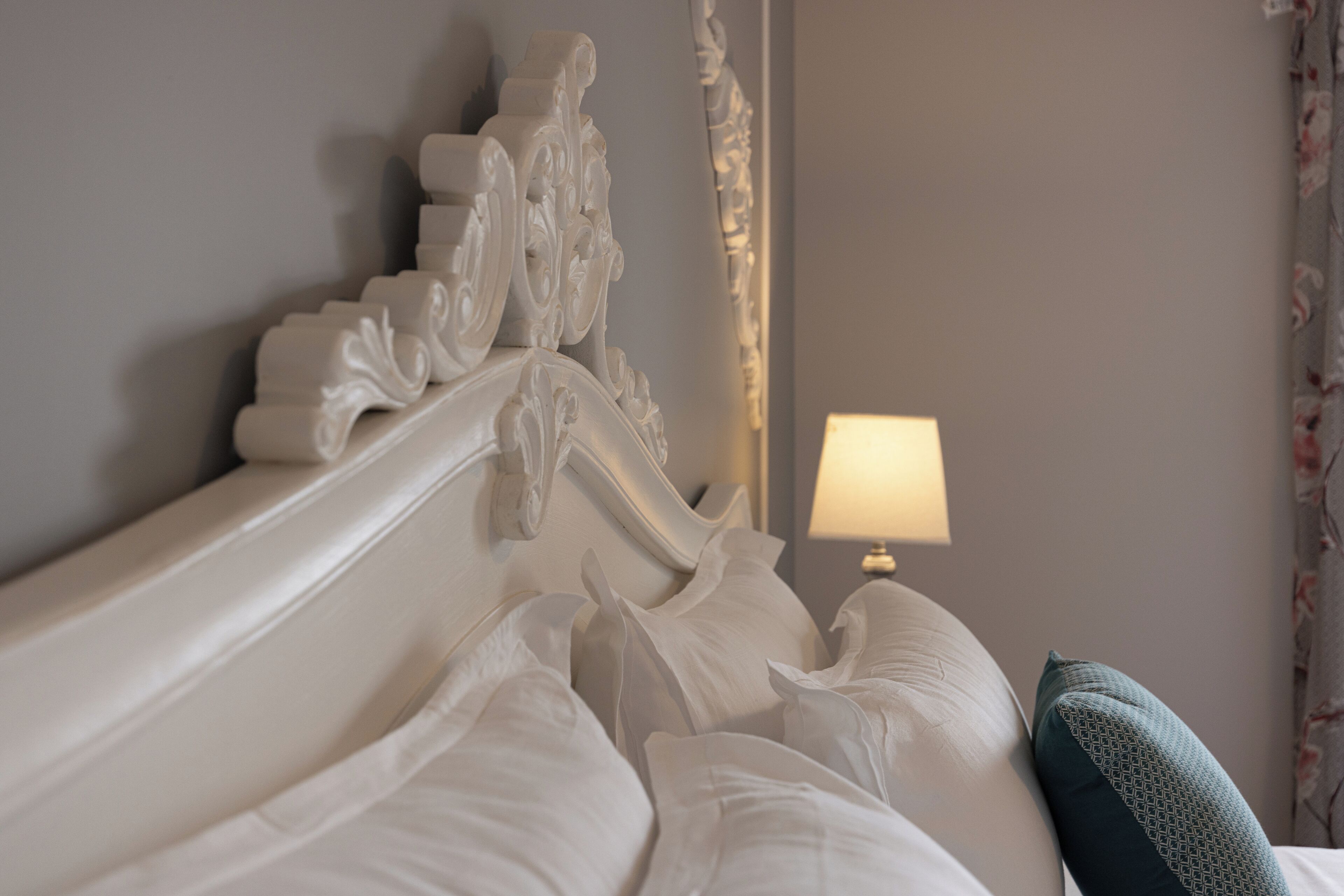 Un lit avec une literie blanche et une tête de lit décorative.