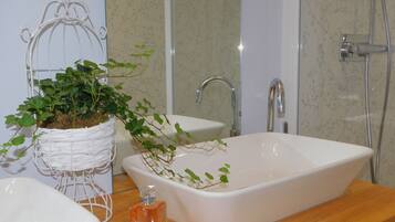 A bathroom with a white sink, a shower, and a decorative birdcage with plants.
