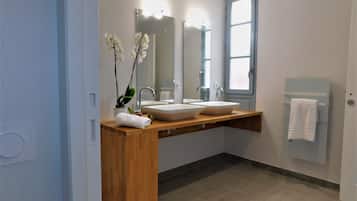 Une salle de bain moderne avec deux vasques, un meuble-lavabo en bois, un grand miroir et une fenêtre.