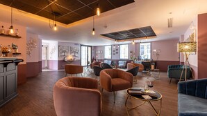 A spacious lounge area with multiple seating options, including sofas and armchairs, and a bar area with bottles on shelves. - Hôtel des Augustins - Boutique Hôtel - Restaurant Gastronomique (Saint-Cyprien)
