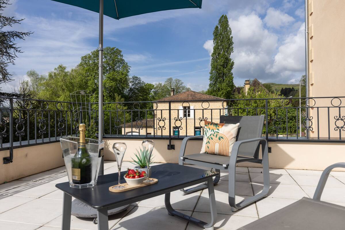 Un balcon avec une table, des chaises et une bouteille de champagne.