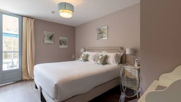 A neatly arranged bedroom with a large bed, bedside lamps, and artwork on the walls.