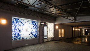 A hotel corridor with a geometric patterned window, a reception desk, and a brick wall. - NOA HOTEL Toyotaminami - Adults Only (Anjo)