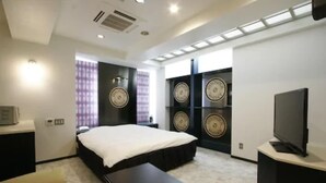 A modern hotel room with a bed, a desk, a television, and decorative wall clocks. - NOA HOTEL Toyotaminami - Adults Only (Anjo)
