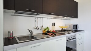 A modern kitchen with dark cabinets, a stainless steel sink, a microwave, and a stove. - Gravedona Aquamarine Apt. 3 (Gravedona)