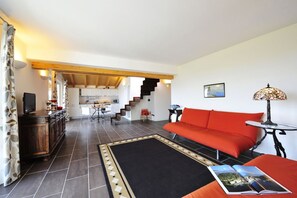 A modern living room with a sofa, a coffee table, and a dining area with chairs and a table.