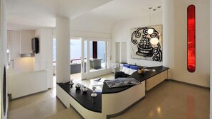 A modern kitchen with a curved island, a large window, and a unique wall art piece. - Villa Parisi (Tremezzina)