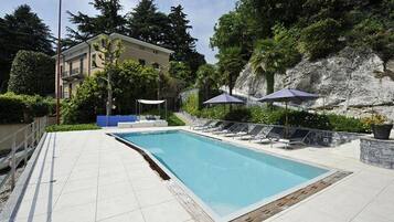 Una piscina al aire libre, sillones reclinables de piscina