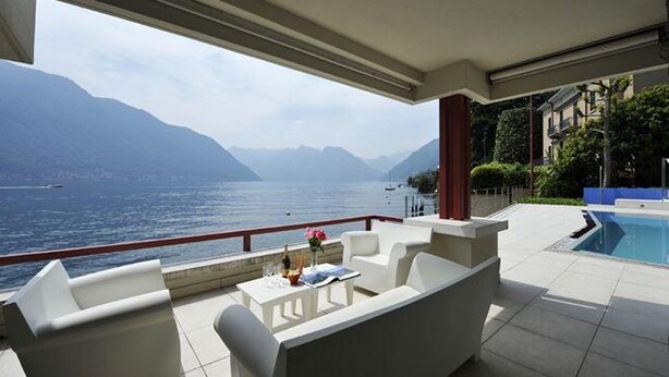 A terrace with a view of the sea and mountains, a pool, and outdoor seating. - Villa Parisi (Tremezzina)
