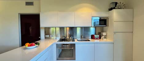 Een moderne keuken met witte kasten, roestvrijstalen apparatuur en een inbouwoven.